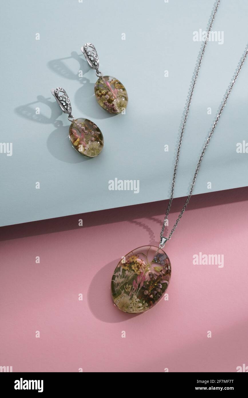 Pendientes de resina y collar con flores naturales en el interior sobre  azul y fondo rosa Fotografía de stock - Alamy