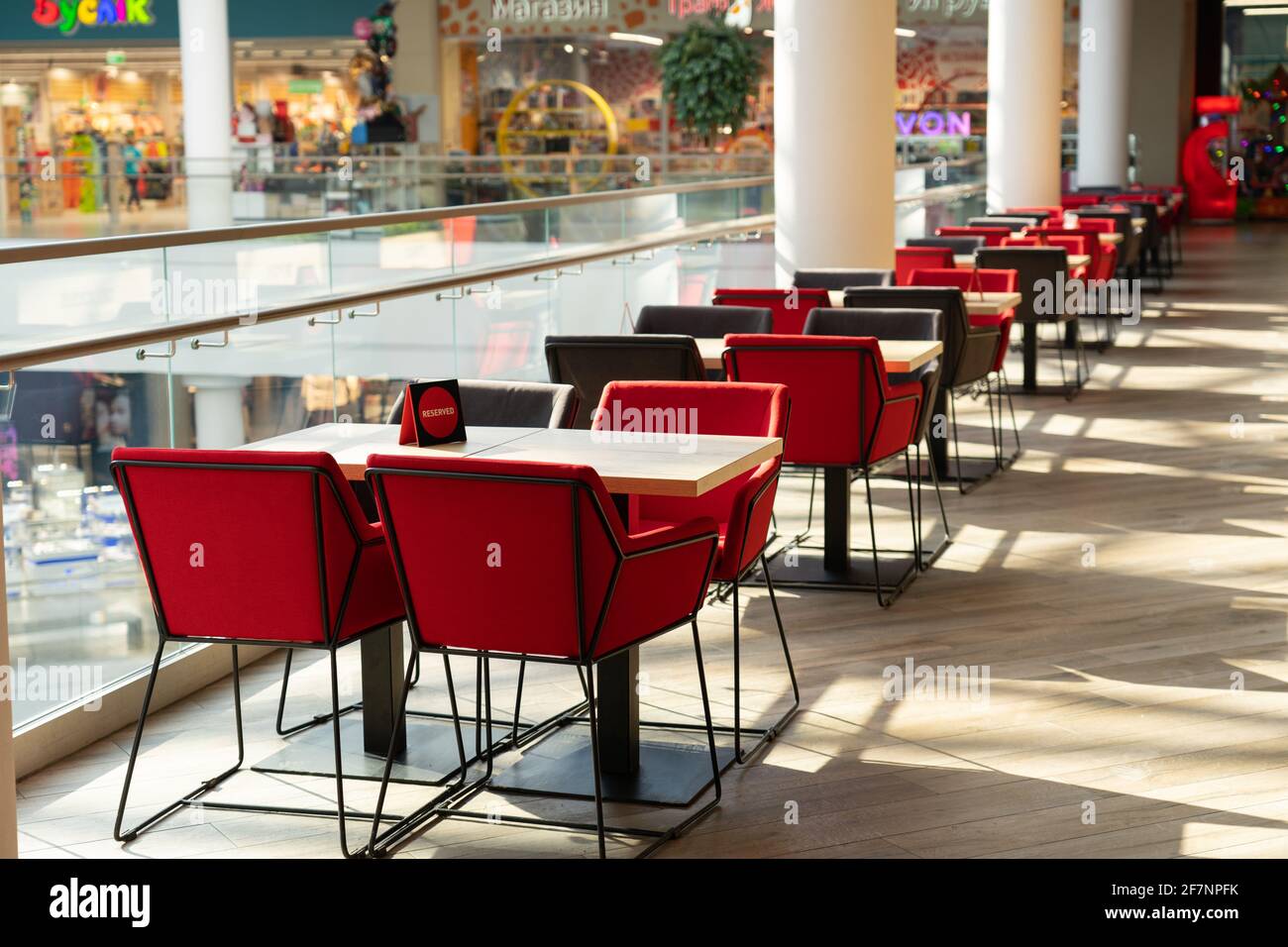 Una fila de mesas con sillas para los visitantes a la zona de comidas de un  moderno centro comercial. La gente admira la hermosa vista durante la  comida Fotografía de stock -