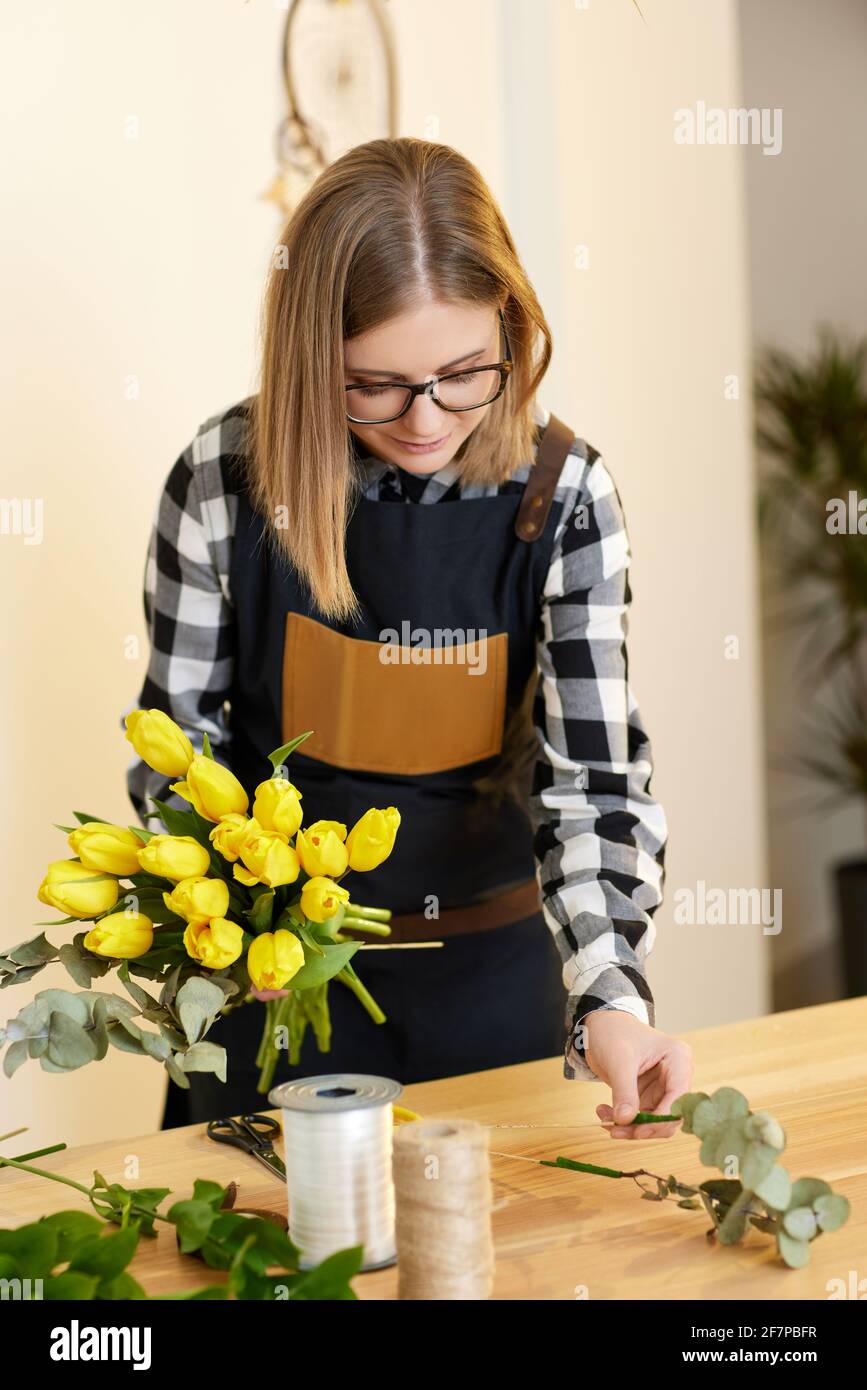 Floristería mujer hace un ramo de tulipanes. Foto de stock