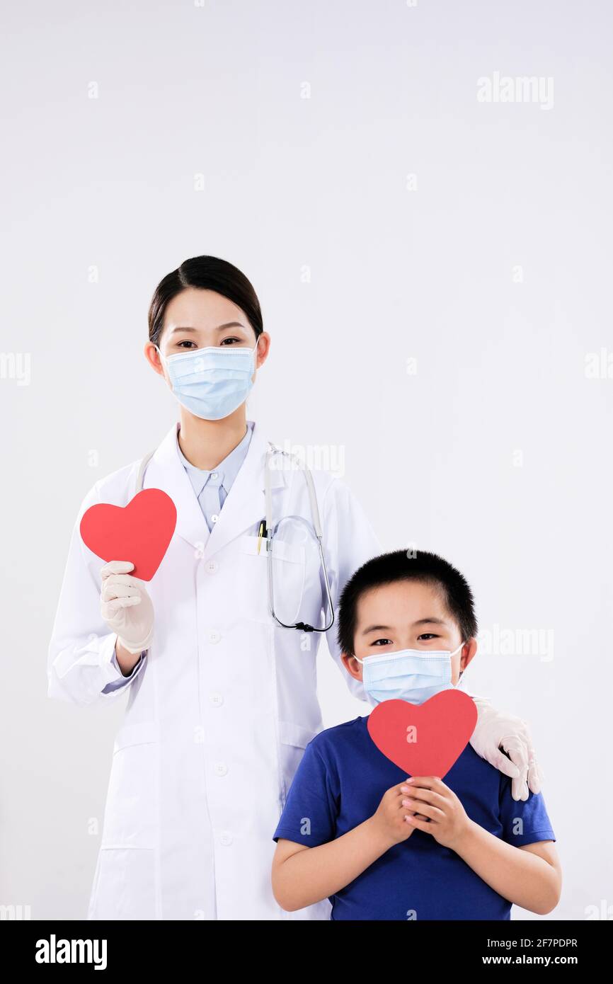 Una mujer médica y un niño pequeño tenían un corazón rojo en la cámara Foto de stock
