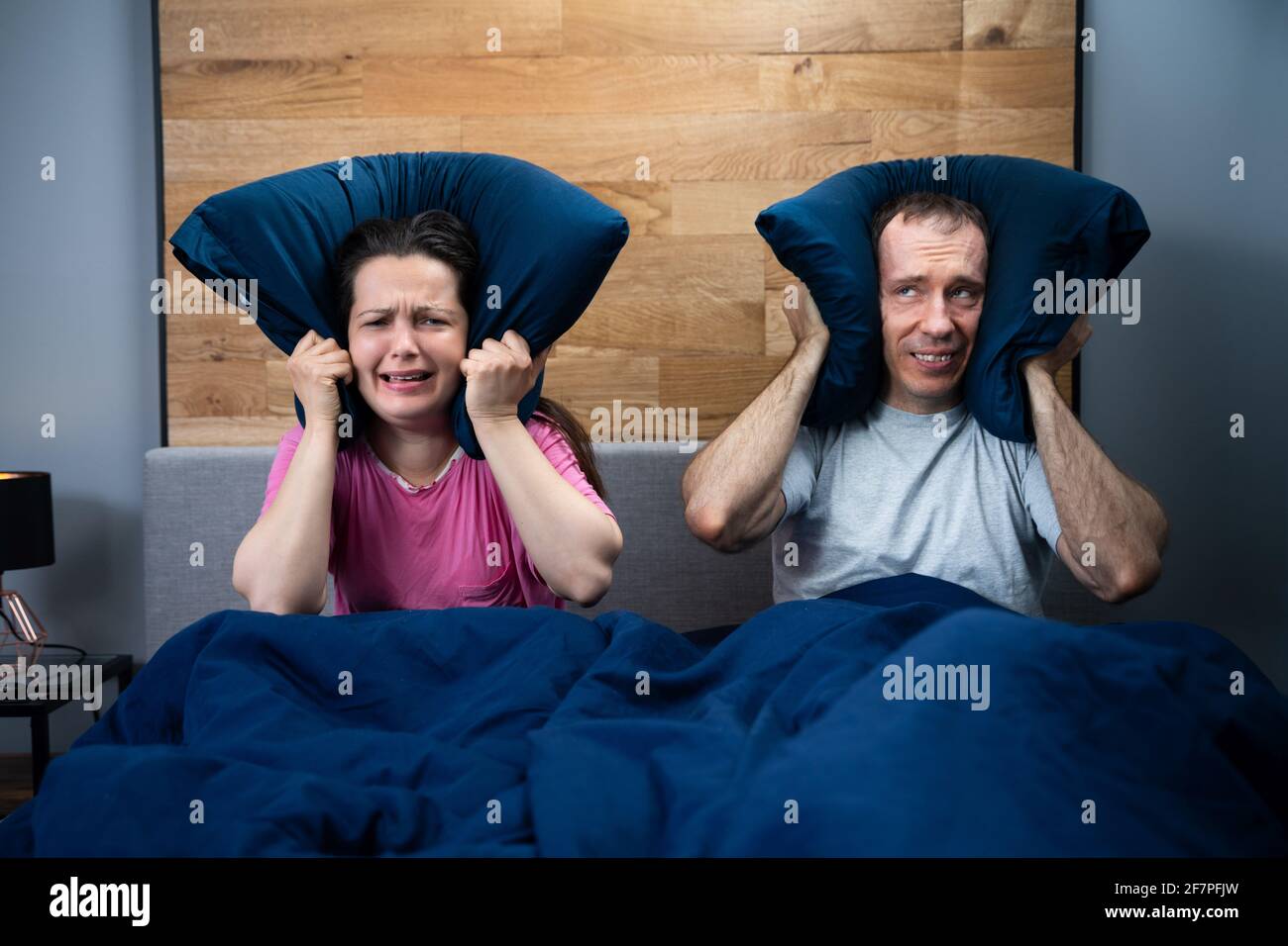 Un vecino ruidoso hace una fiesta ruidosa mientras una pareja durmiendo en la cama Foto de stock