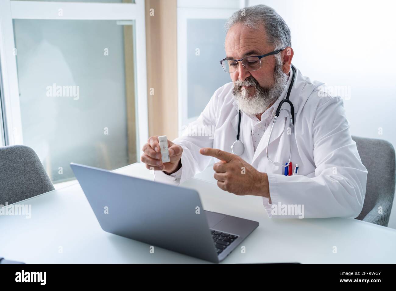Médico que tiene una videoconferencia con un paciente que muestra PCR Resultado de la prueba Covid-19 Foto de stock