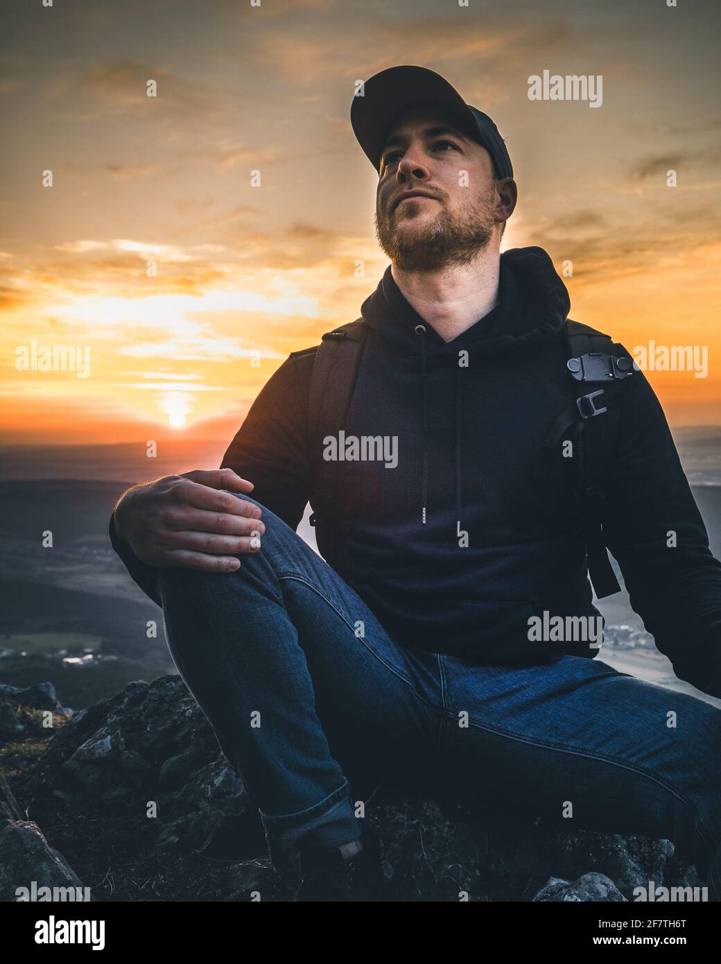 Hombre con una sudadera mirando una colorida puesta de sol montañas  Fotografía de stock - Alamy