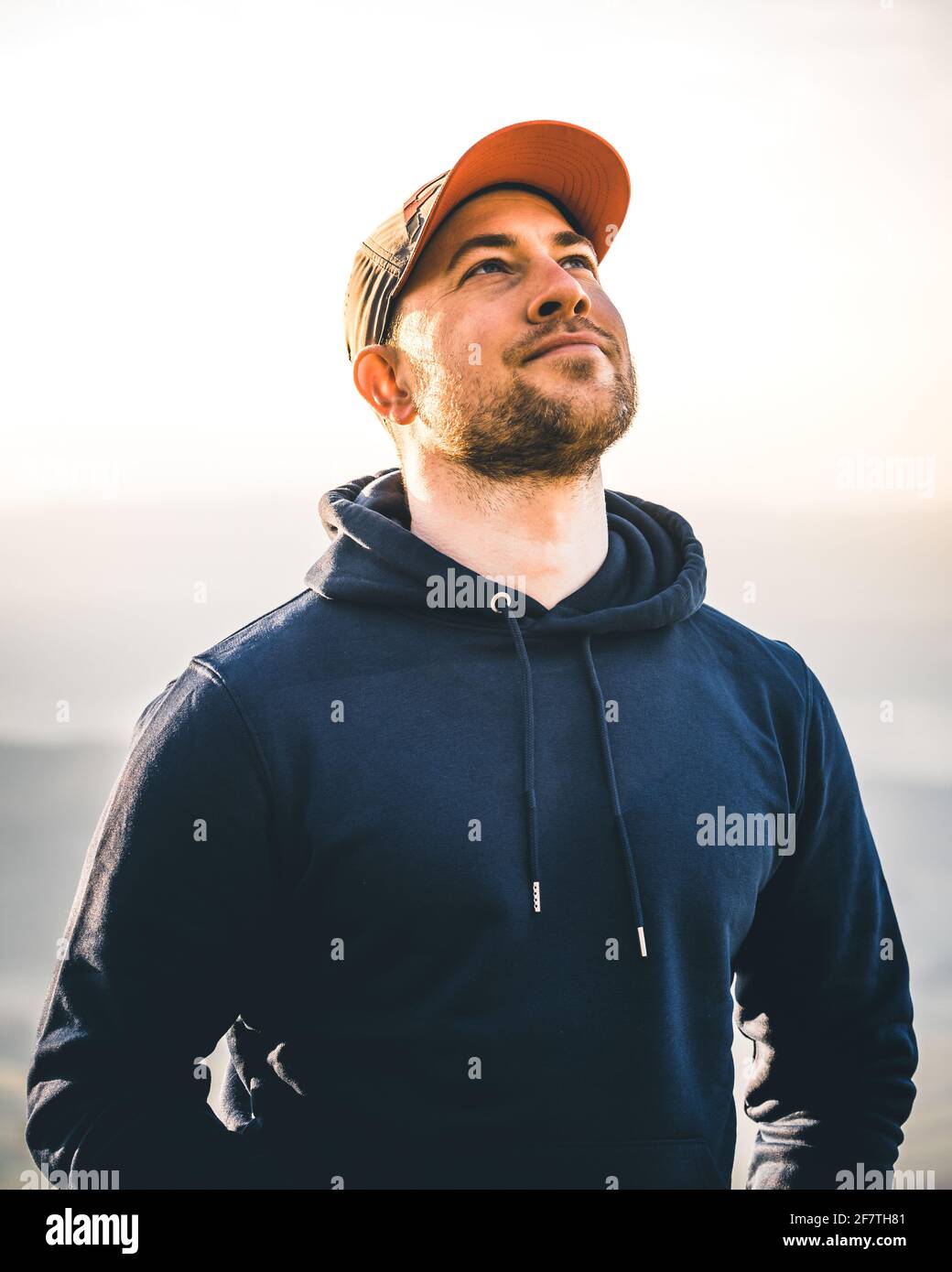 Hombre con una sudadera mirando una colorida puesta de sol montañas  Fotografía de stock - Alamy