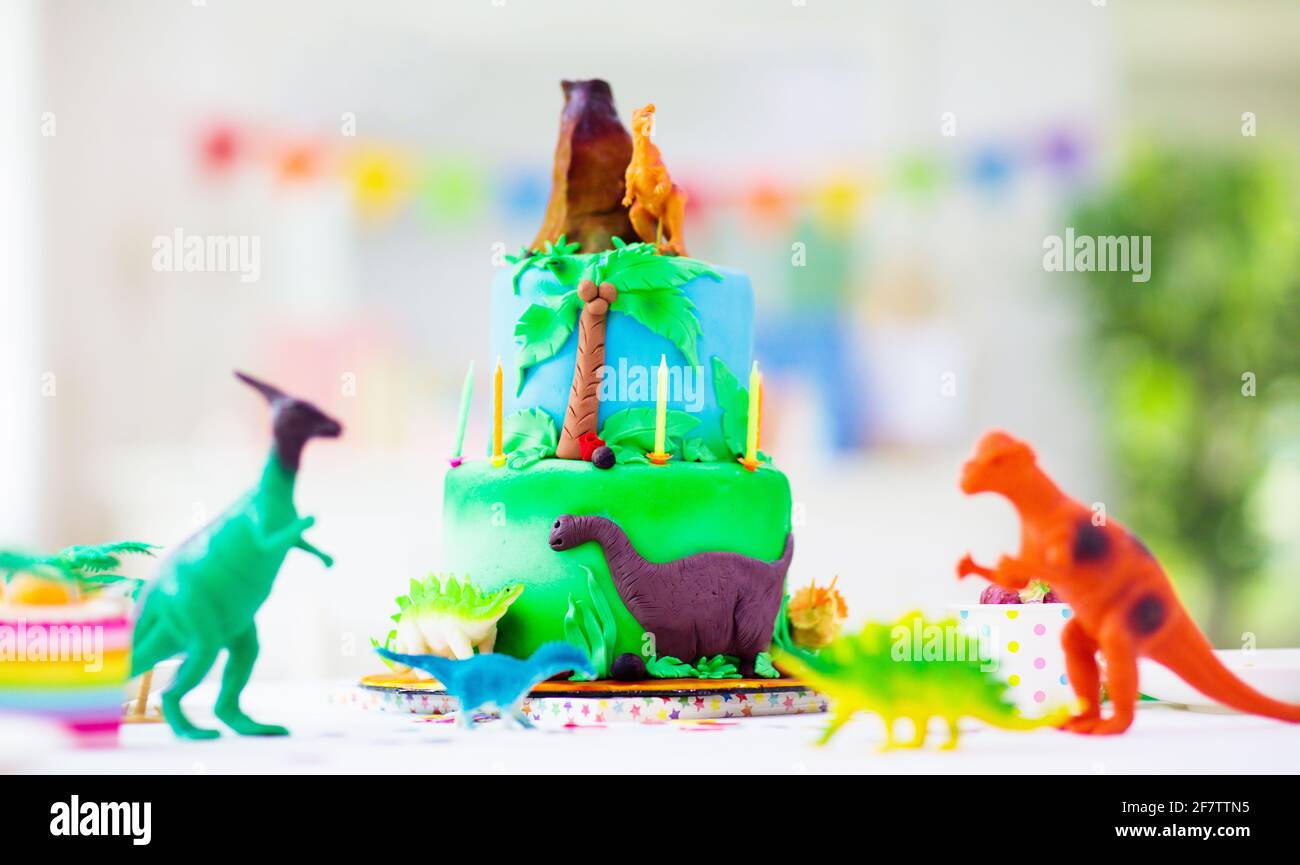 Fiesta de cumpleaños de los niños. Pastel de dinosaurio tema. Niña soplando  velas y abriendo regalos. Evento para niños. Decoración para la celebración  temática de los dinosaurios Fotografía de stock - Alamy