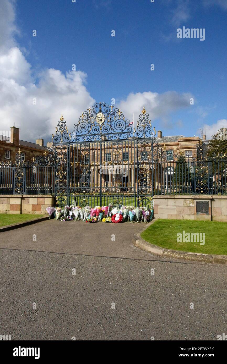 Hillsborough Castle, Hillsborough, County Down, Irlanda del Norte, Reino Unido. 10 de abril de 2021. Con la bandera de la Unión a media asta, se han dejado tributos florales fuera de las puertas de la residencia oficial de HM la Reina en Irlanda del Norte, mientras el público lamenta la pérdida del príncipe Felipe, duque de Edimburgo, que murió ayer. Crédito: David Hunter/Alamy Live News. Foto de stock