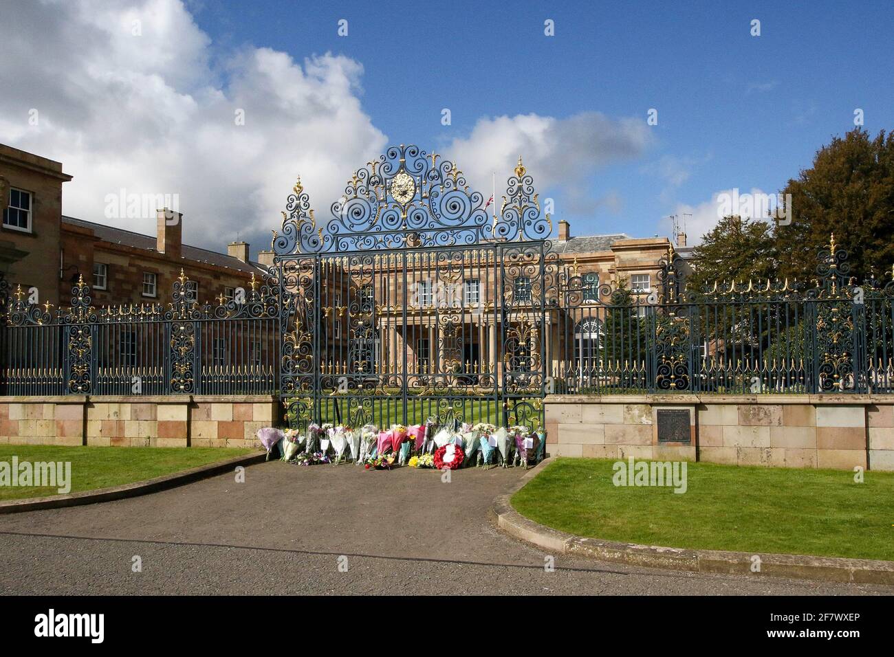 Hillsborough Castle, Hillsborough, County Down, Irlanda del Norte, Reino Unido. 10 de abril de 2021. Con la bandera de la Unión a media asta, se han dejado tributos florales fuera de las puertas de la residencia oficial de HM la Reina en Irlanda del Norte, mientras el público lamenta la pérdida del príncipe Felipe, duque de Edimburgo, que murió ayer. Crédito: David Hunter/Alamy Live News. Foto de stock