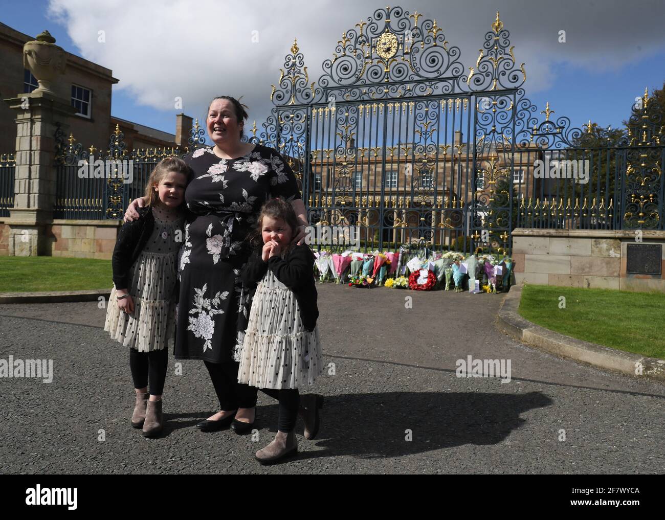Naomi Armstrong-Cotter y sus hijas Lillie, de 6 años (izquierda) y Essie, de 5 años, después de poner flores a las puertas del Castillo de Hillsborough en Irlanda del Norte, tras el anuncio de la muerte del Duque de Edimburgo a la edad de 99 años. Fecha de la foto: Sábado 10 de abril de 2021. Foto de stock