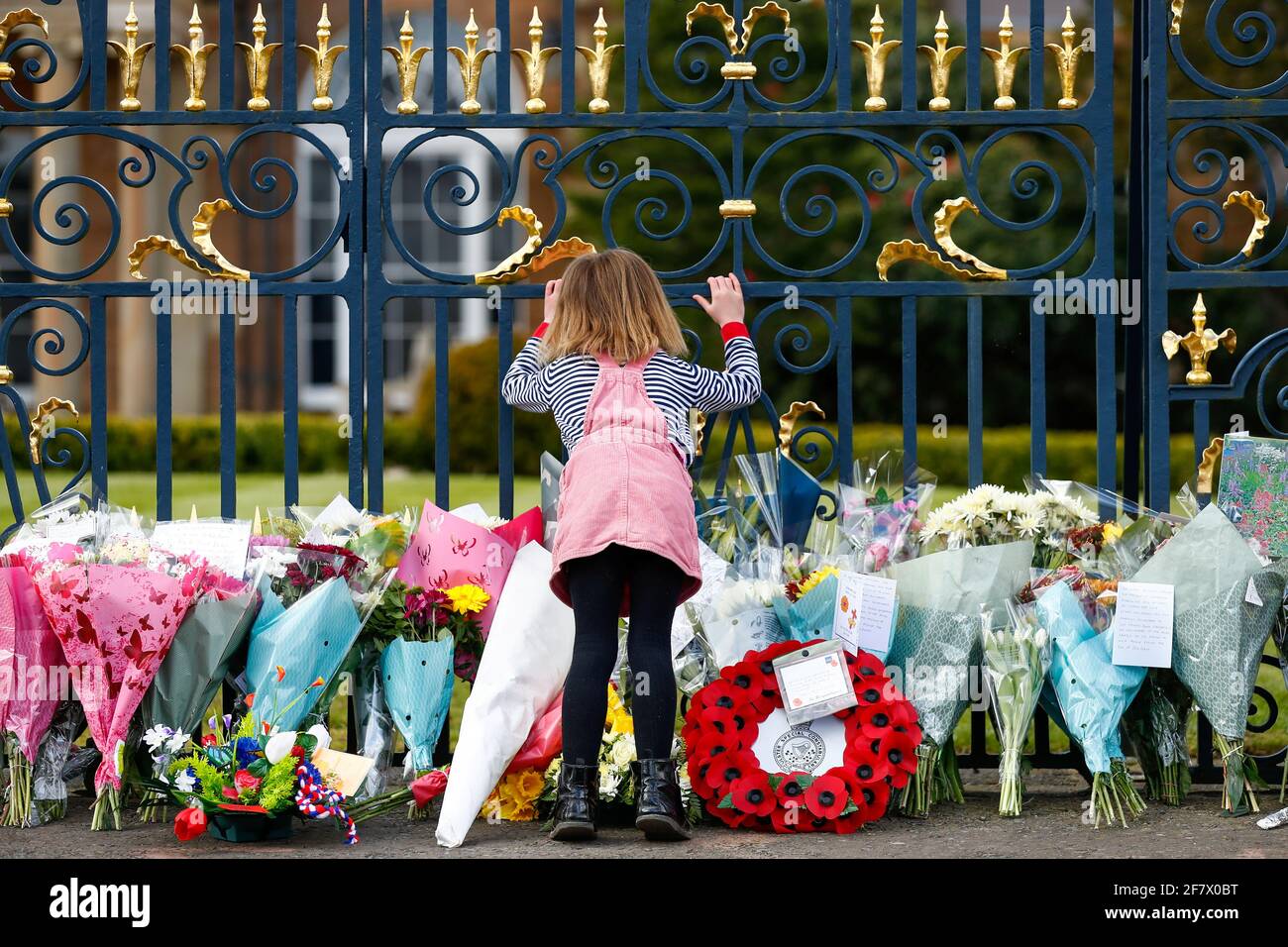 Una niña está de pie delante de las flores colocadas en el Castillo de Hillsborough después de que el Príncipe Felipe de Gran Bretaña, esposo de la Reina Isabel, murió a la edad de 99 años, en Hillsborough, Irlanda del Norte, 10 de abril de 2021. REUTERS/Jason Cairnduff Foto de stock