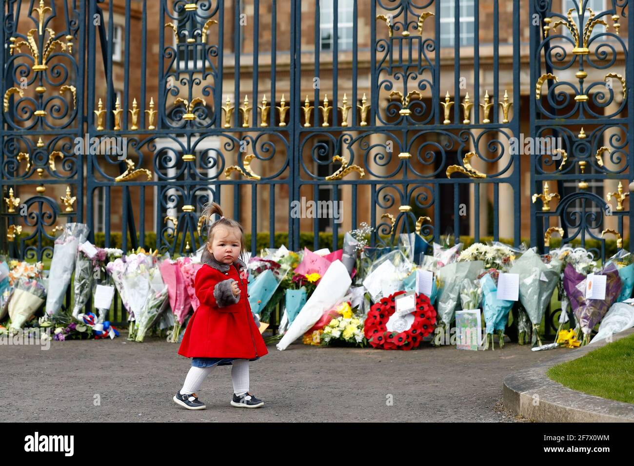 Una niña camina delante de las flores colocadas en el Castillo de Hillsborough después de que el Príncipe Felipe de Gran Bretaña, esposo de la Reina Isabel, murió a la edad de 99 años, en Hillsborough, Irlanda del Norte, 10 de abril de 2021. REUTERS/Jason Cairnduff Foto de stock