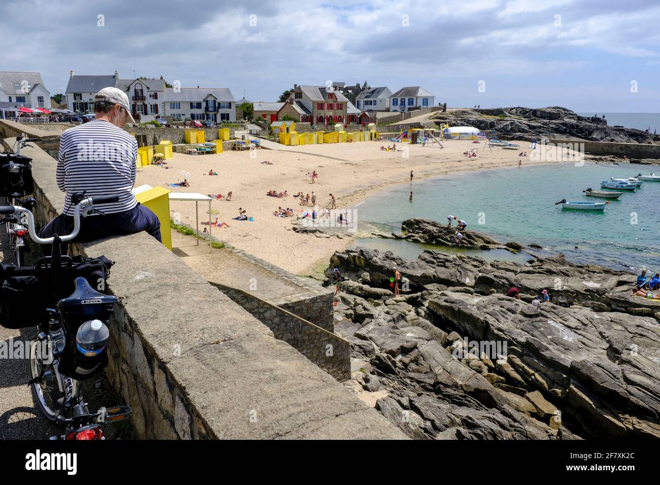 Frankreich, Batz-sur-Mer, 16.07.2020: Eine Fahrradfahrerin macht eine Pause auf der Mauer ueber dem Strand und Hafen von Saint Michel in Batz-sur-Mer Foto de stock