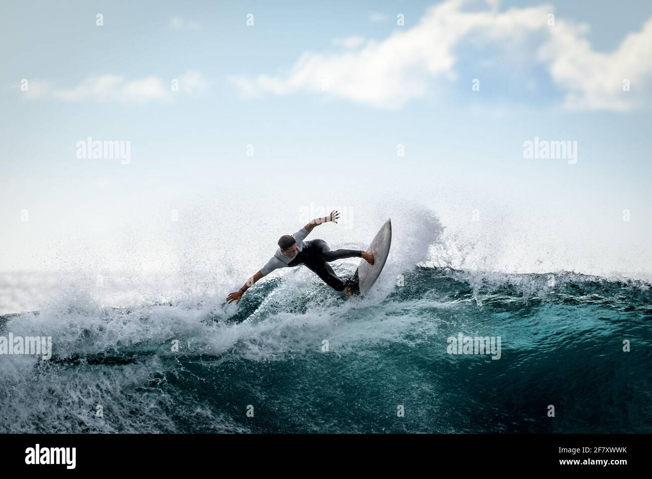 Surfista joven con traje de neopreno disfrutando de grandes olas en Tenerife,  Islas Canarias. Niño deportivo montando su tabla de surf en la ola del  océano. Maki adolescente valiente Fotografía de stock -