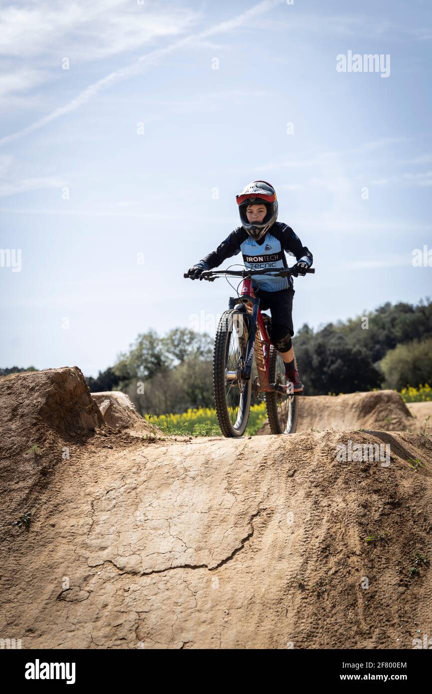 Niño practicando saltos en bicicleta de montaña en un parque de bicicletas en Forallac, Cataluña, España Foto de stock