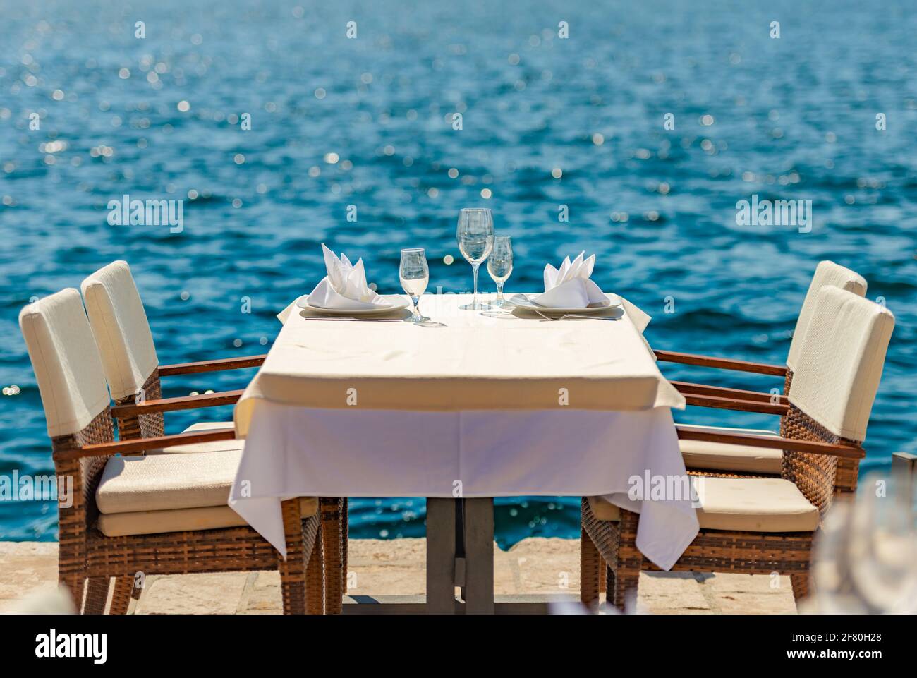 Café callejero vacío en el mar en Perast, Montenegro. Mesa y sillas junto al agua. Relájese y viaje en Balcans, Europa. Foto de stock