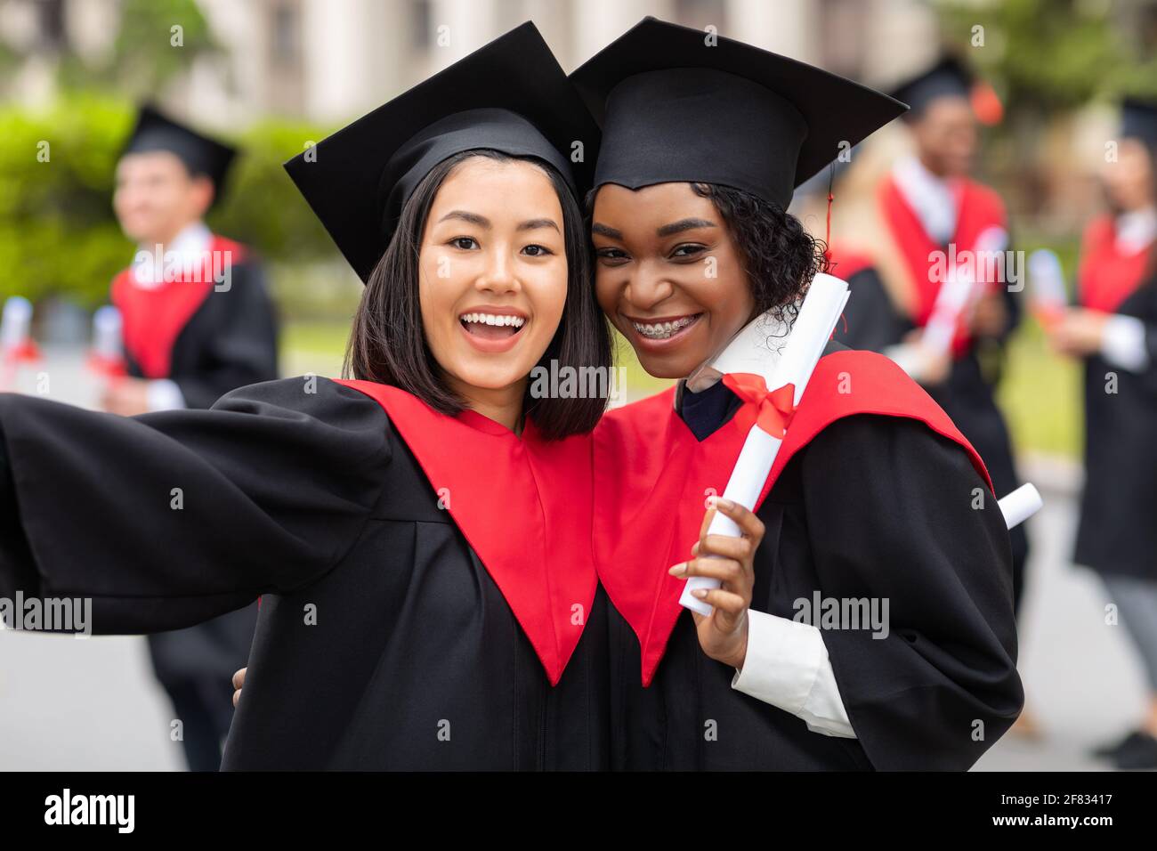 Alegres señoras jóvenes en trajes de graduación tomando selfie Fotografía  de stock - Alamy