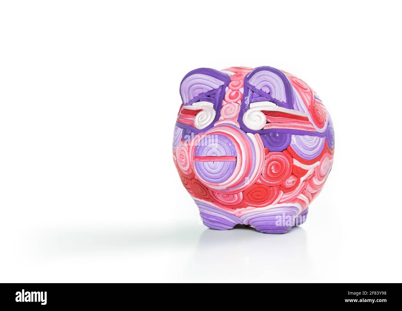 Único banco de piggy, banco de peniques o caja de dinero. Adorable escultura artesanal de cerdo hecha de arcilla con remolinos y líneas de color blanco, rosa violeta y rojo. Foto de stock