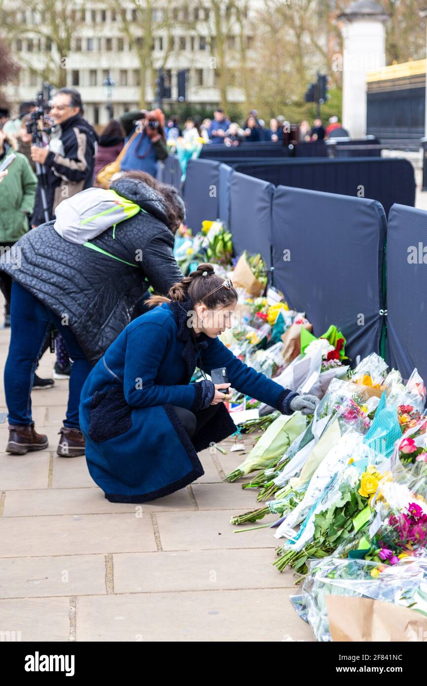 11 de abril de 2021, Londres, Reino Unido - Mujer poniendo flores como tributo al Príncipe Felipe, Duque de Edimburgo en las afueras del Palacio de Buckingham después de su muerte el 9th de abril Foto de stock