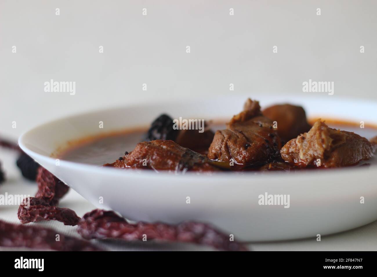 curry de pescado con salsa roja preparada al estilo tradicional de kerala. El pescado utilizado es el Bluefin trévally, conocido localmente como vatta. Grabado sobre fondo blanco Foto de stock