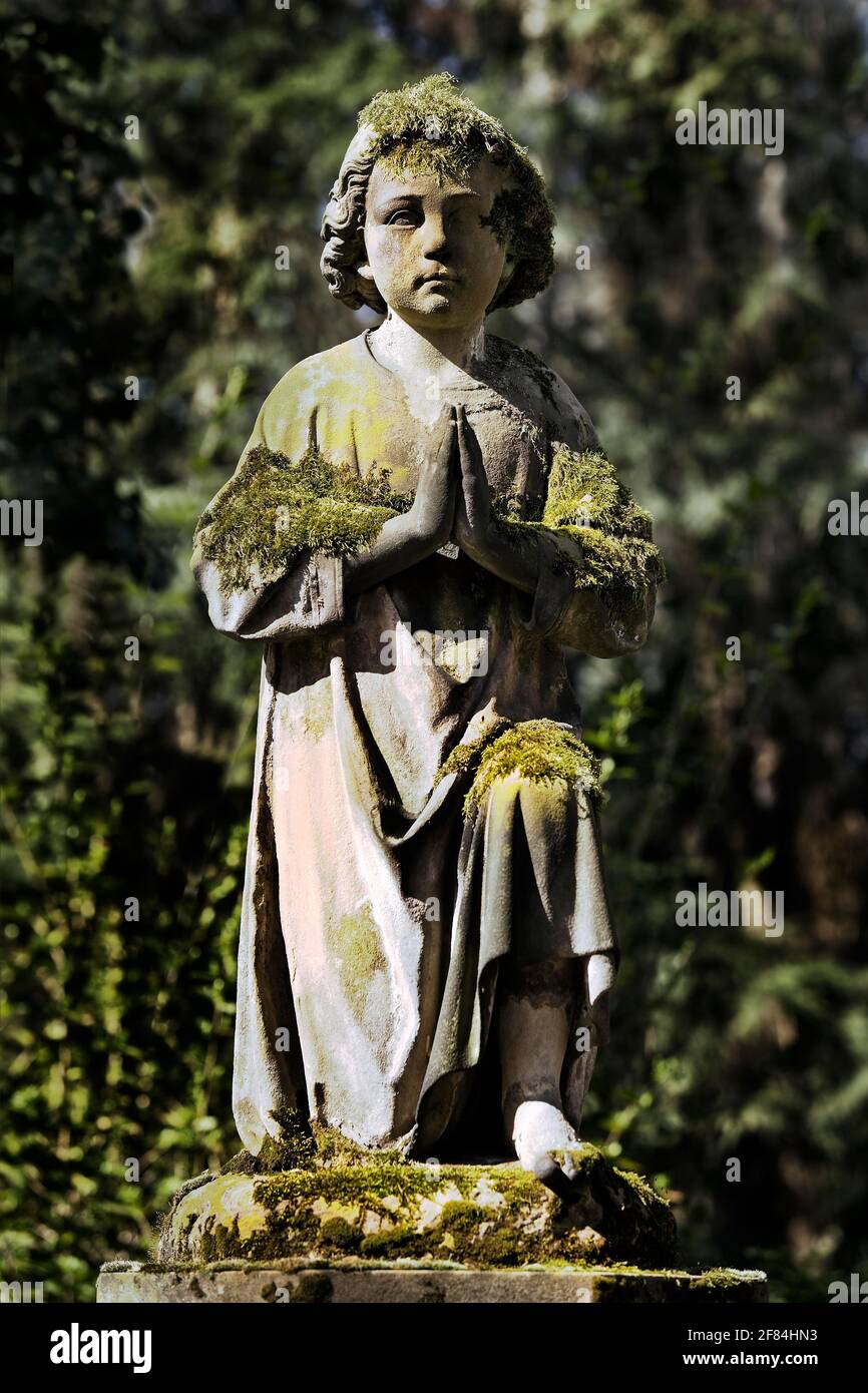 Escultura de tumbas rezando con musgo en el cementerio de Melaten, Colonia, Renania del Norte-Westfalia, Alemania Foto de stock