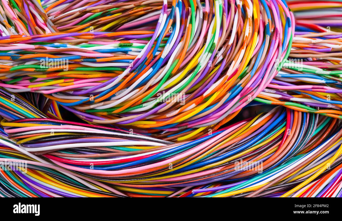 Fondo colorido de cables multinúcleo. Primer plano del enredo del mazo de cables. Hermosas trenzas de cables eléctricos en textura abstracta coloreada. Tecnología. Foto de stock