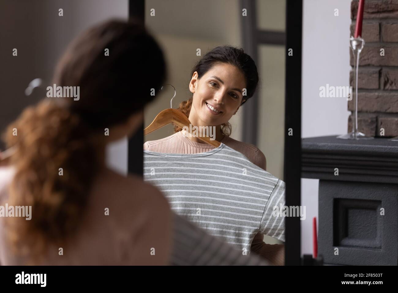 Espejo reflejo de la despreocupada mujer milenaria eligiendo atuendo Foto de stock