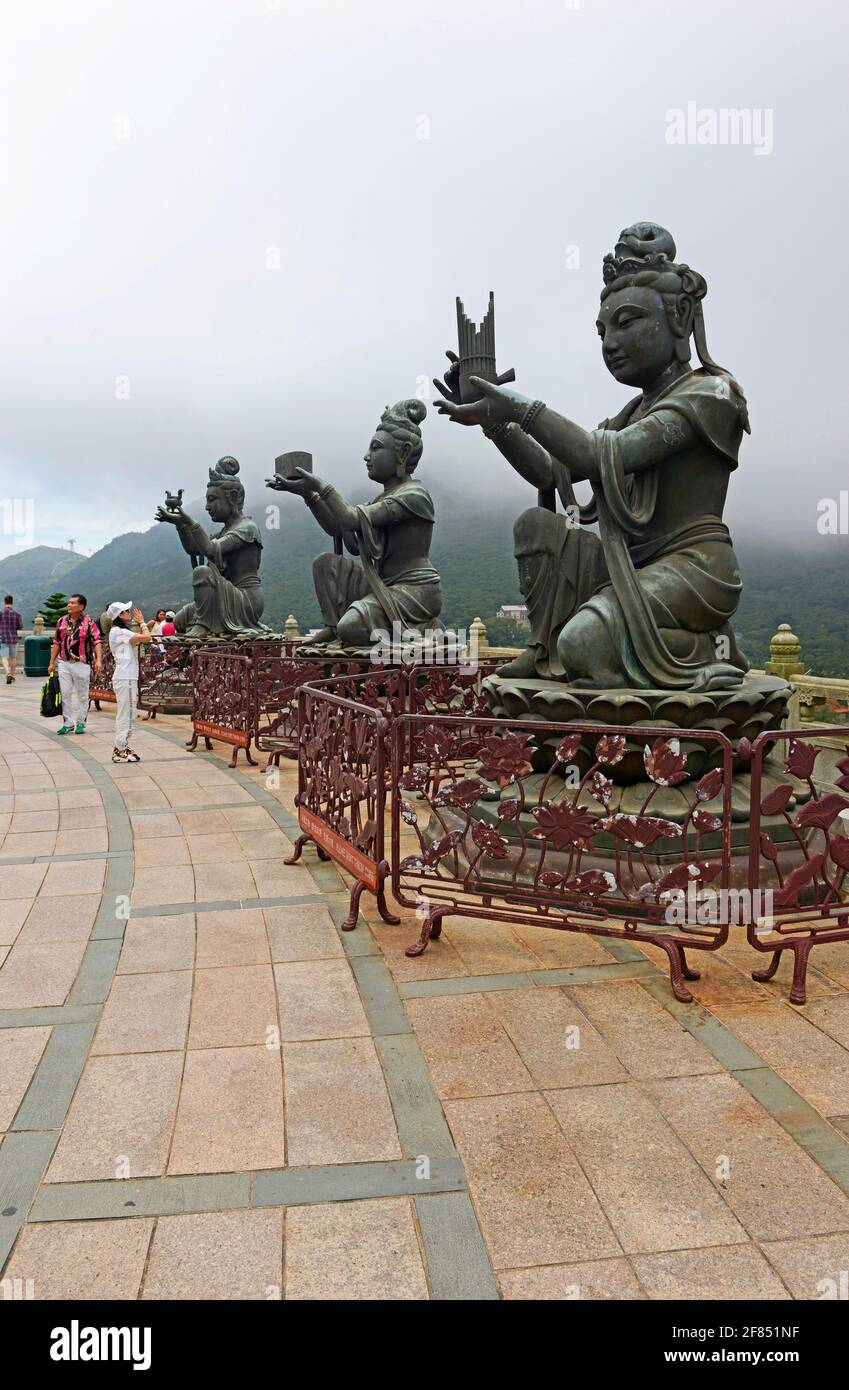 Tres estatuas de bodhissatvas hacen ofrendas en el podio del buda Tian Tan en el monasterio Po Lin en Ngongping en la isla Lantau, Hong Kong, China Foto de stock