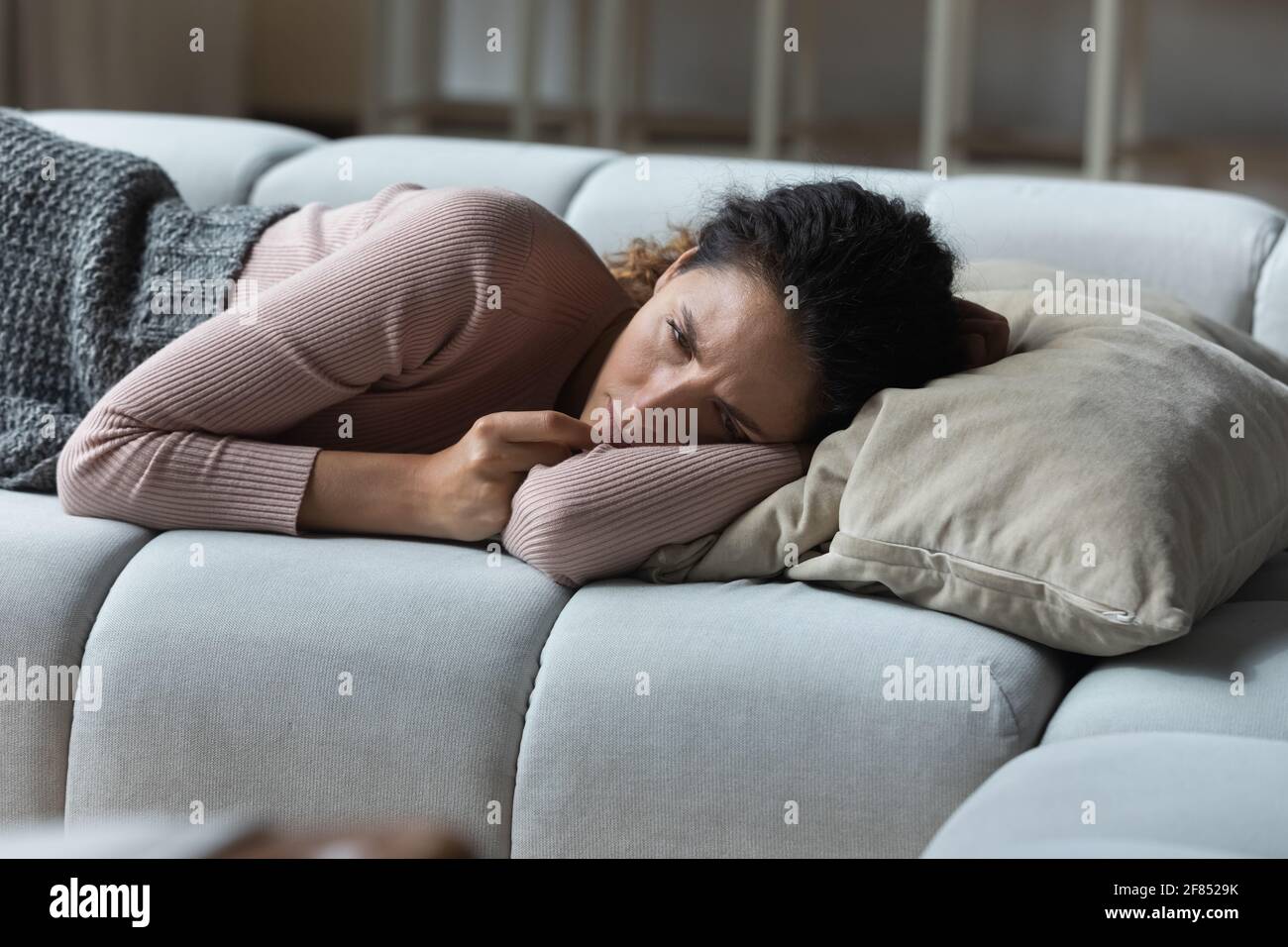 Estresado triste mujer latina acostada en el sofá incapaz de dormir Foto de stock