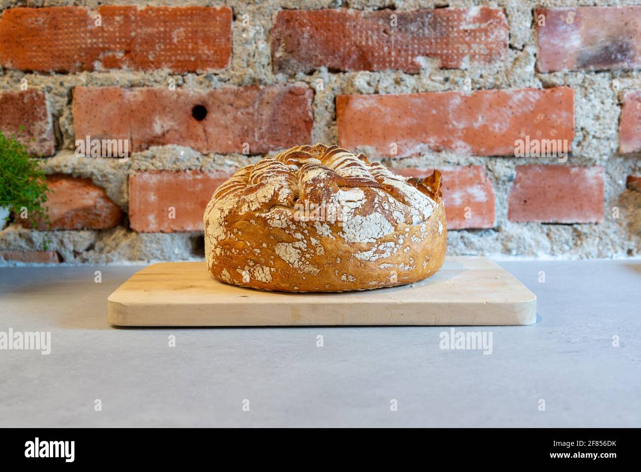 Pan casero de masa de harina, listo para ser comido frente a una pared de ladrillo. Foto de stock