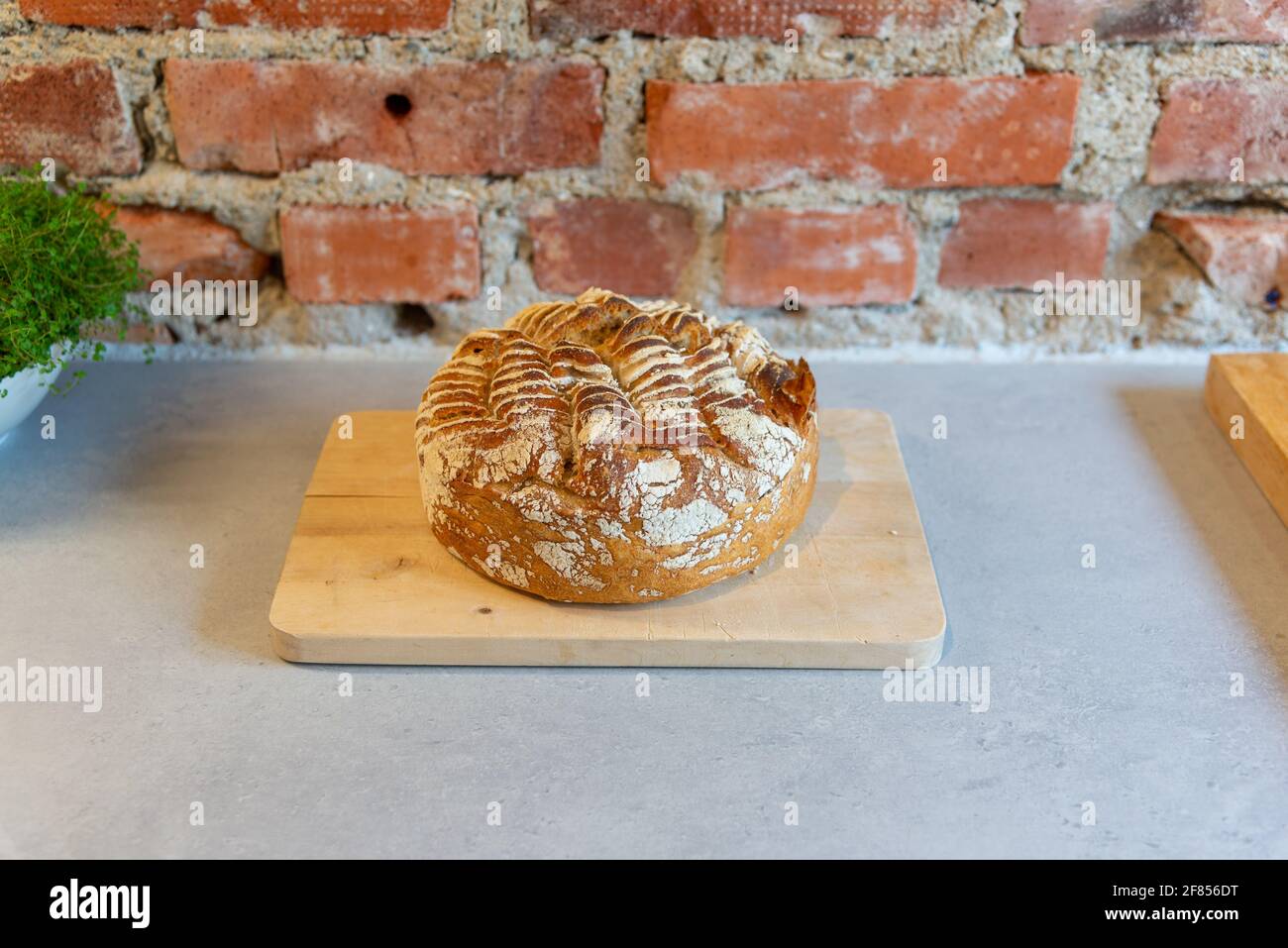 Pan casero de masa de harina, listo para ser comido frente a una pared de ladrillo. Foto de stock