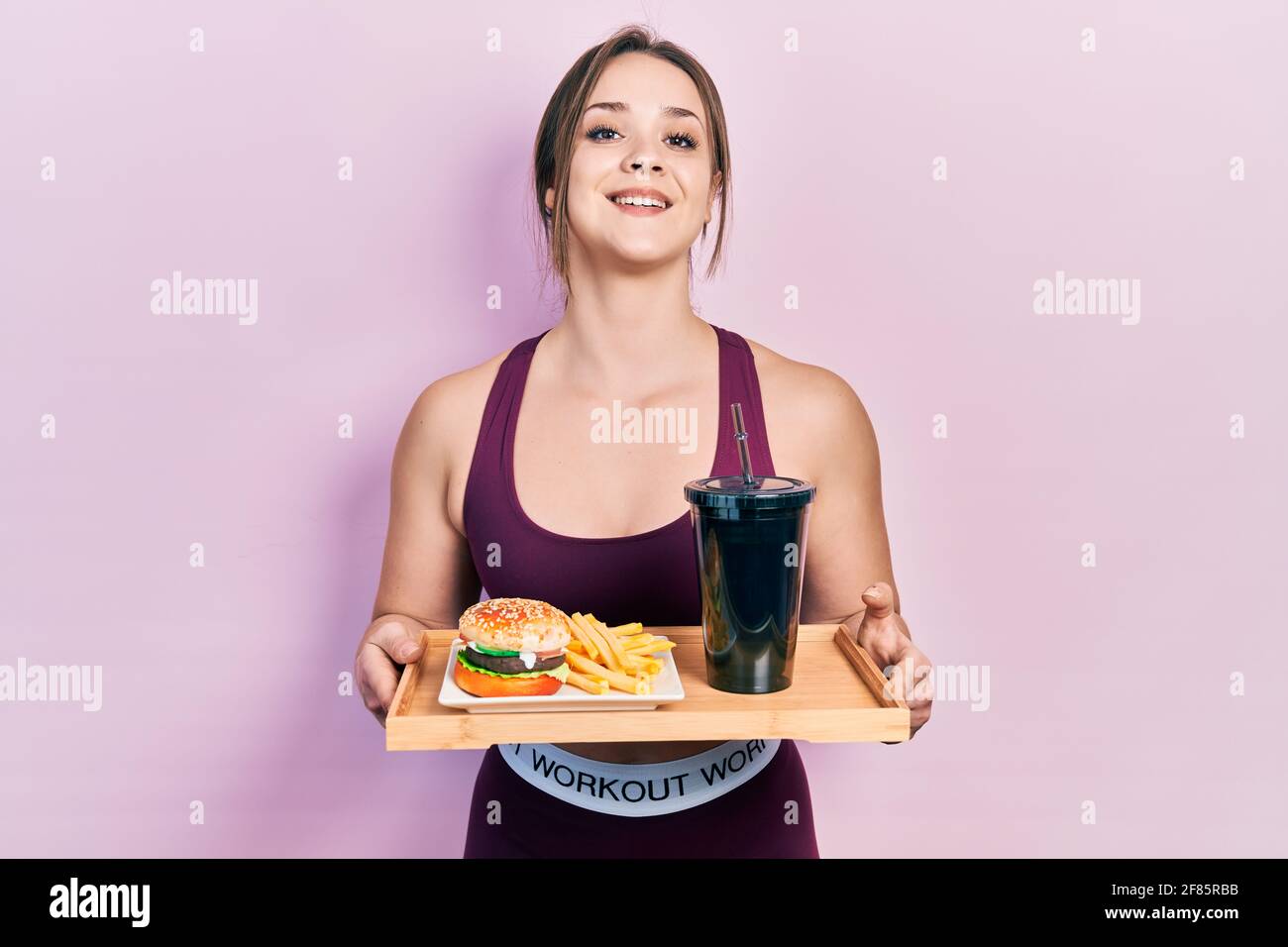 Chica hispana joven usando ropa deportiva comiendo una hamburguesa clásica  sabrosa con patatas fritas y soda sonriendo y riendo mucho en voz alta  porque divertido chiste loco Fotografía de stock - Alamy