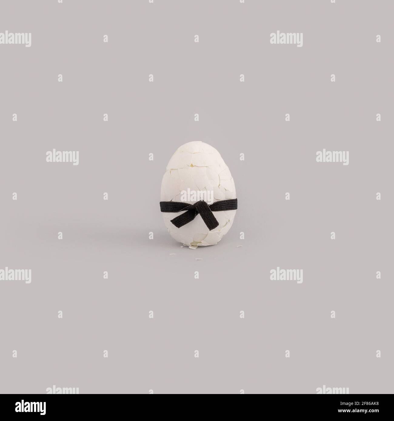 Tiro vertical de un huevo blanco con una cinta negra arco aislado sobre  fondo gris Fotografía de stock - Alamy