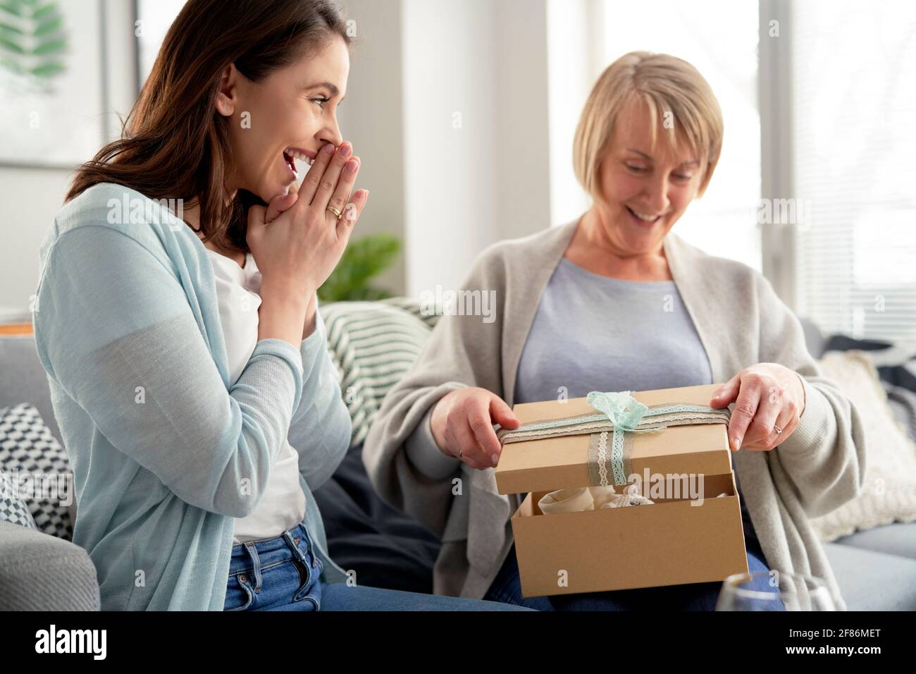 Mujer emotiva esperando a mamá para abrir el regalo Foto de stock