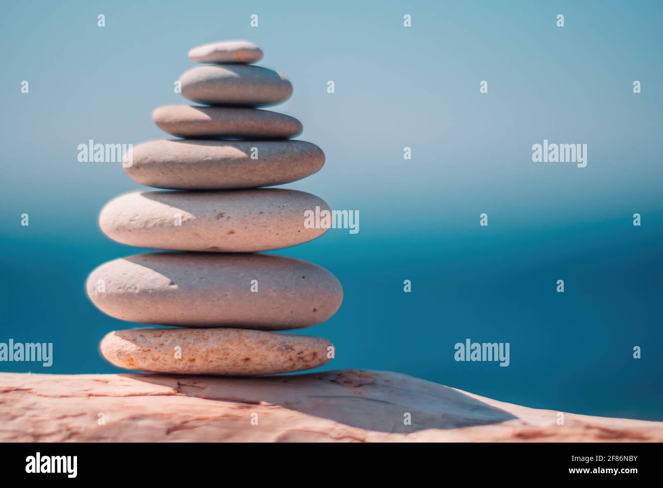 Piedras piramidales en la orilla del mar en un día soleado sobre el fondo azul del mar. Felices vacaciones. Playa de guijarros, mar tranquilo, destino de viaje. Concepto de feliz Foto de stock