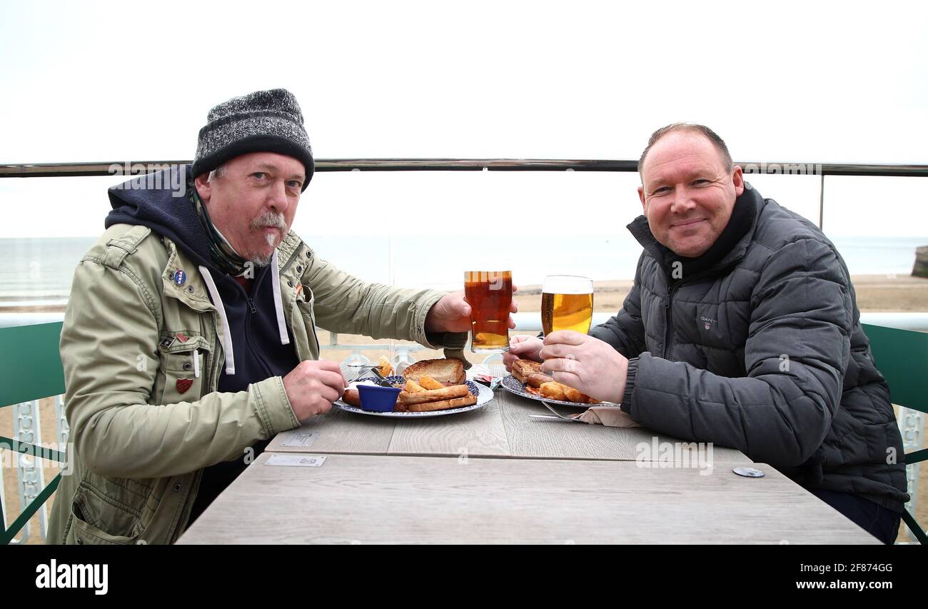 Gary Gearing (izquierda) y Lee Cooper disfrutan de su desayuno y una pinta en el Royal Victoria Pavilion en Ramsgate, Kent, mientras Inglaterra da otro paso atrás hacia la normalidad con la mayor relajación de las restricciones de bloqueo. Fecha de la foto: Lunes 12 de abril de 2021. Foto de stock