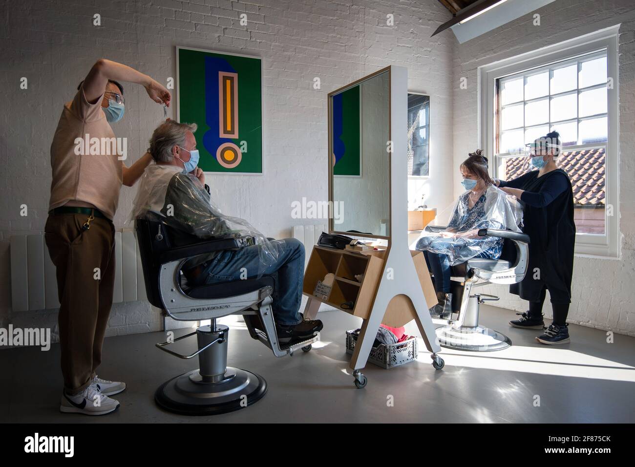 Los clientes tienen su corte de pelo en la reapertura de Flint Hair en Norwich, Norfolk, ya que Inglaterra da otro paso atrás hacia la normalidad con la mayor relajación de las restricciones de cierre. Fecha de la foto: Lunes 12 de abril de 2021. Foto de stock