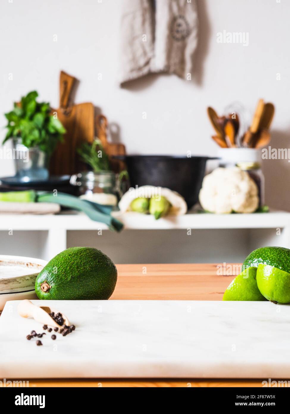 Mesa de madera con fruta verde y tabla de mármol y fondo de cocina borroso. CopySpace. Concepto de preparación de alimentos, cocina en el fondo. Foto de stock