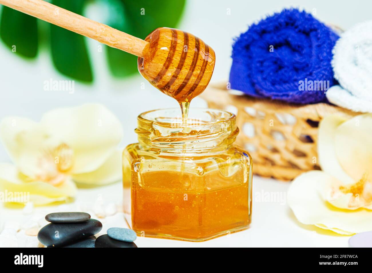 Tratamiento de spa con miel. Miel de oro en un frasco, flores de orquídeas,  toallas y velas perfumadas. Cuidado natural de la piel en el hogar  Fotografía de stock - Alamy