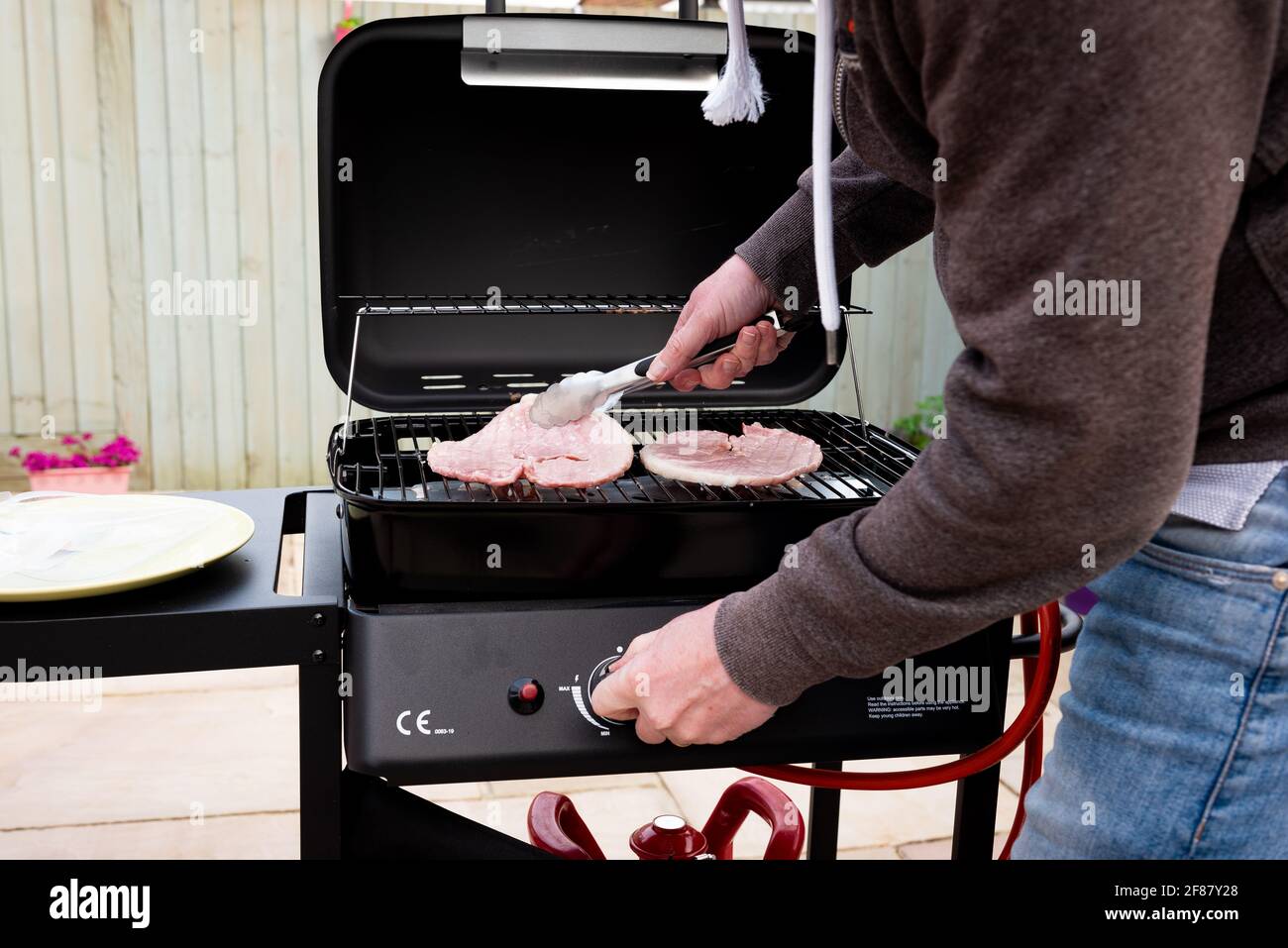 primer plano de las personas manos cocinando carne en el jardín Barbacoa Foto de stock