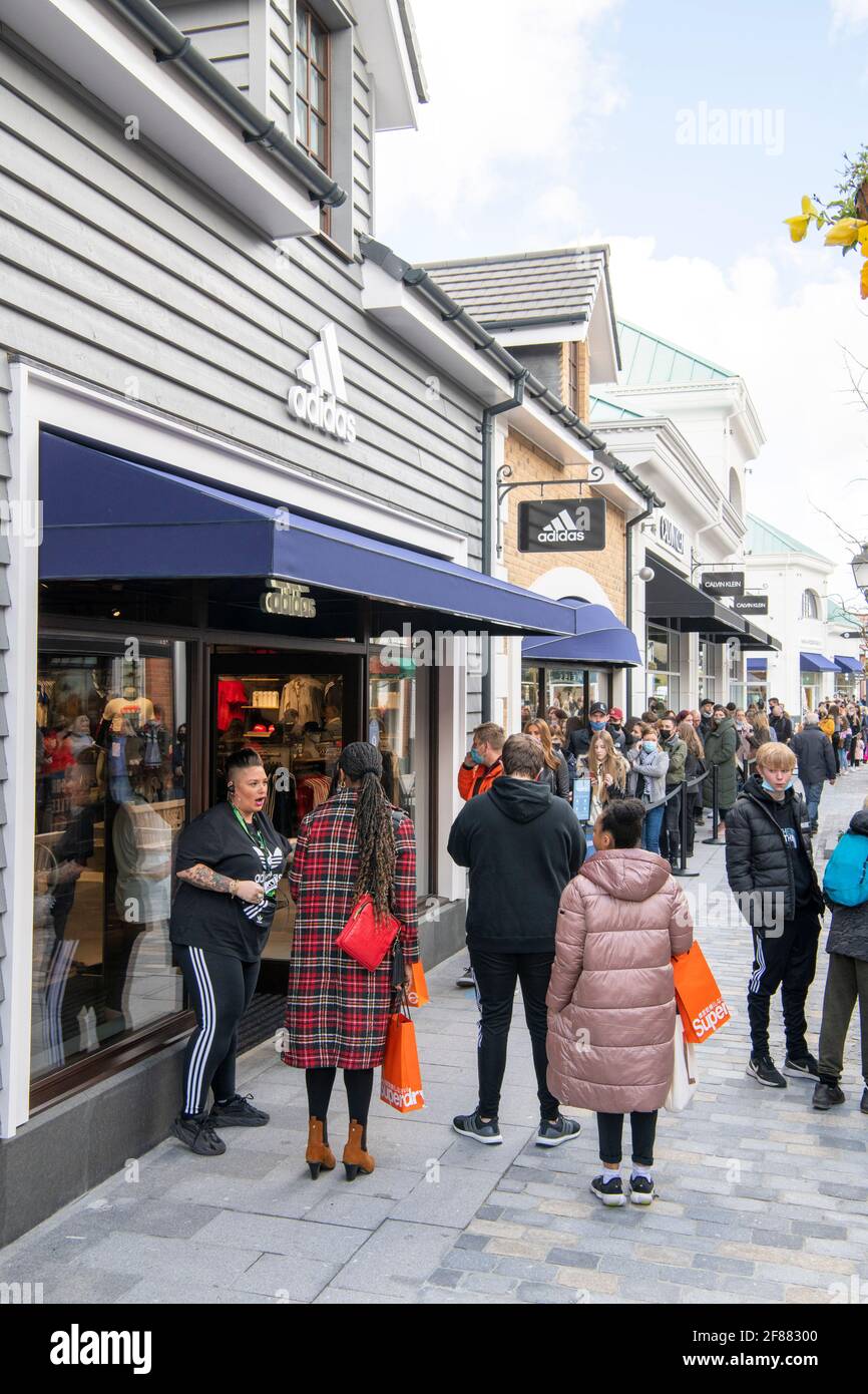 CANNOCK, STAFFORDSHIRE, REINO UNIDO. 12th de Abr de 2021. Las tiendas que no son esenciales pueden abrir sus puertas a los compradores hoy en día. El complejo comercial Designer Outlet en Cannock, Staffordshire, abrió sus puertas por primera vez hoy tras haberse completado recientemente. Las colas grandes esperan fuera de los almacenes del diseñador. Alrededor de 50 compradores esperan para llegar a Adidas. Crédito: Richard Grange/Alamy Live News Foto de stock