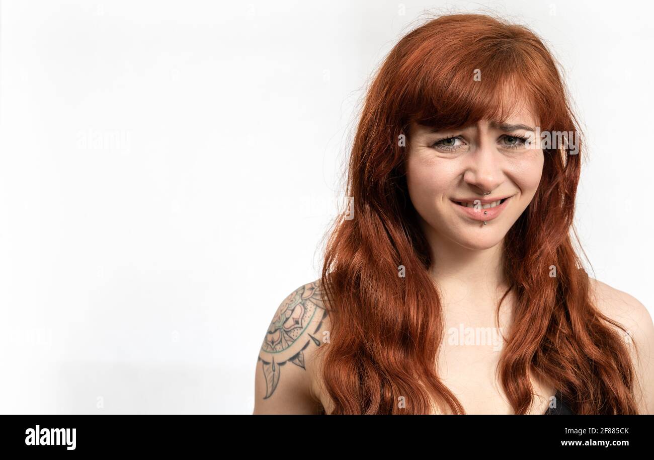 Retrato de una mujer con el pelo rojo frente al blanco fondo con expresión de cara disgustada y espacio en blanco Foto de stock