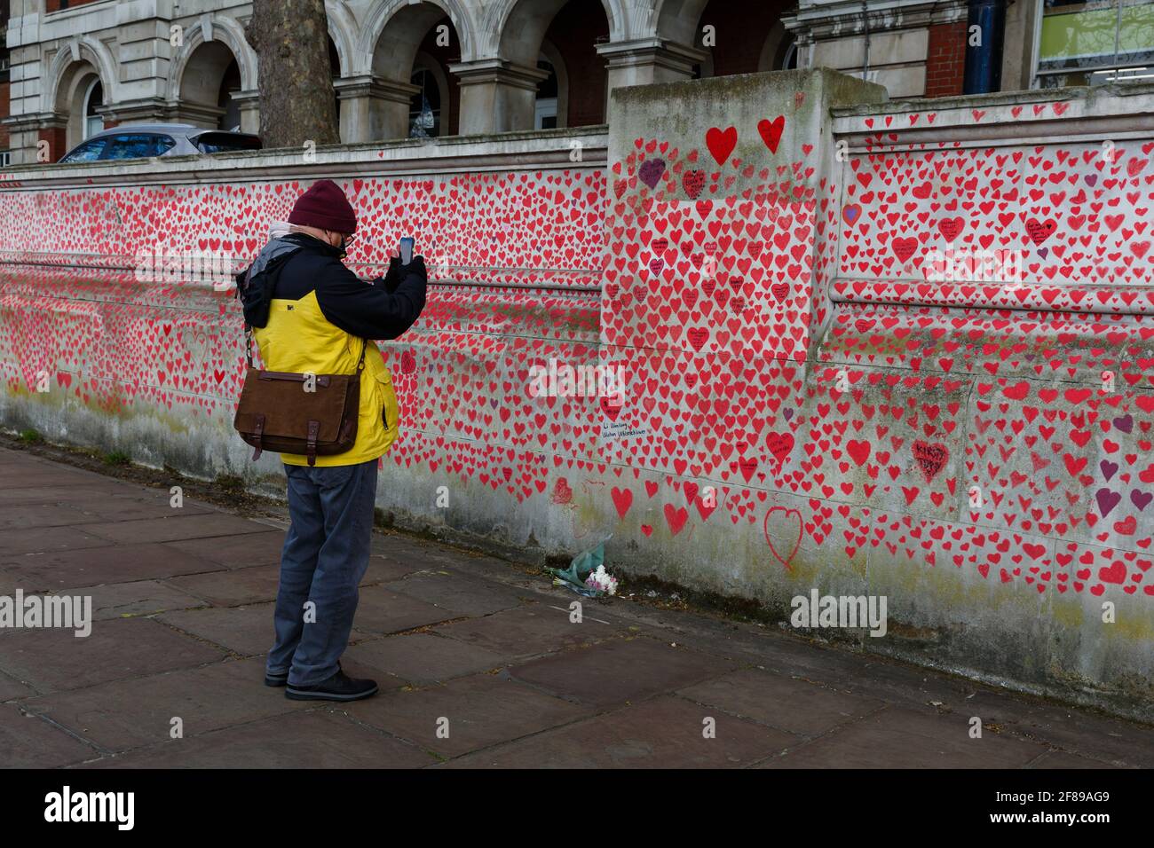 Los transeúntes observan los corazones rojos pintados en el Nacional Covid Memorial Wall como homenaje a las víctimas británicas De Corornavirus Foto de stock