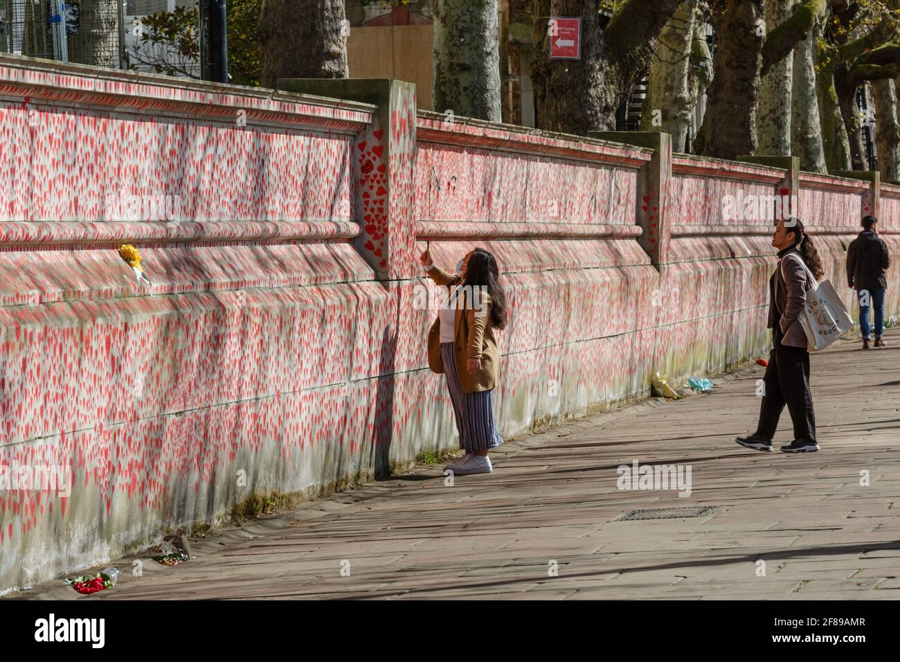 Los transeúntes observan los corazones rojos pintados en el Nacional Covid Memorial Wall como homenaje a las víctimas británicas De la pandemia del Coronavirus Foto de stock