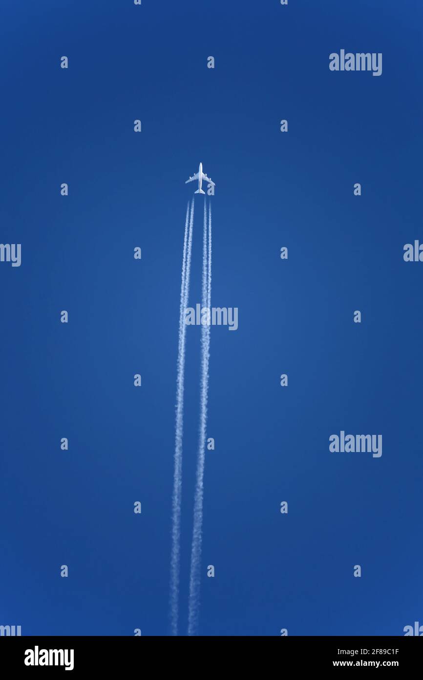 Avión con contravias en cielo azul claro, altitud de crucero. Los aviones dejan los senderos blancos, o los contrails, en sus estelas por la misma razón que usted puede alguiense Foto de stock