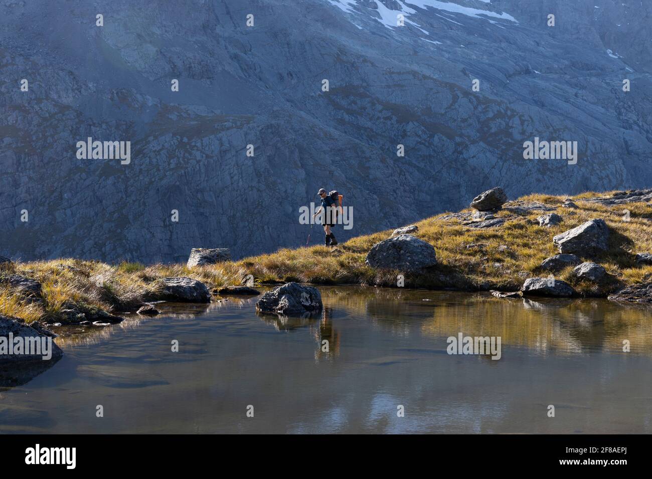 El excursionista pasa por un tarn alpino en las montañas de Nueva Zelanda Foto de stock