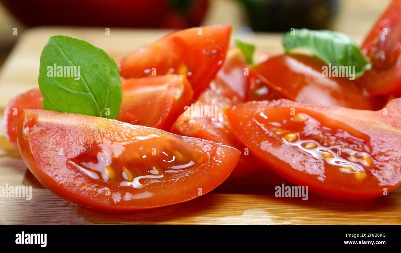 Tomate cherry en rodajas en trozos sobre tabla de corte de madera para preparar comida deliciosa. Cocina casera. Foto de stock