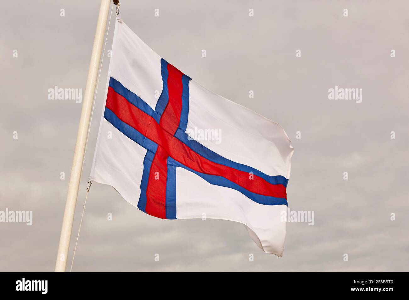 Islas Feroe bandera ondeando bajo un cielo nublado. Horizontal Foto de stock