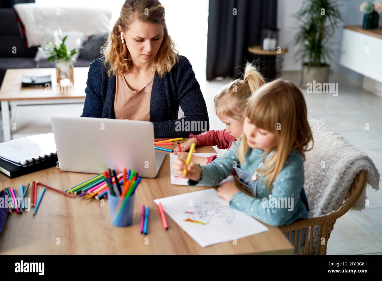 Madre ocupada trabajando en casa con sus hijas Foto de stock