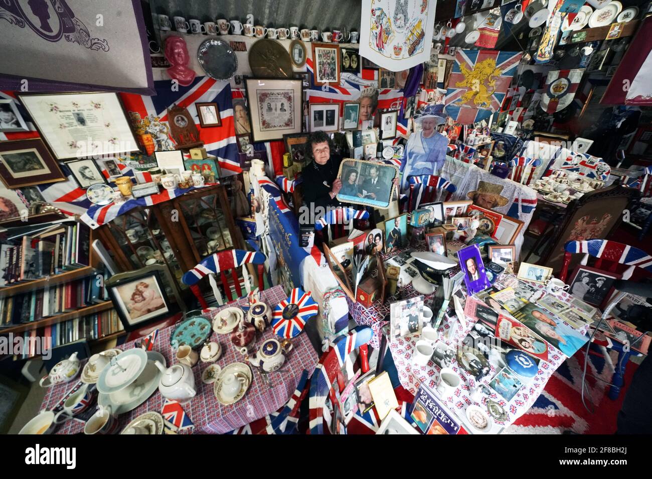 Anita Atkinson arreglando la Reina y la sección del Duque de Edimburgo de su colección real de recuerdos, una de las más grandes del mundo, en su casa en Crook, Condado de Durham. La niña de 64 años dice que fue devastada al escuchar la noticia de la muerte del príncipe Felipe. Fecha de la foto: Martes 13 de abril de 2021. Foto de stock
