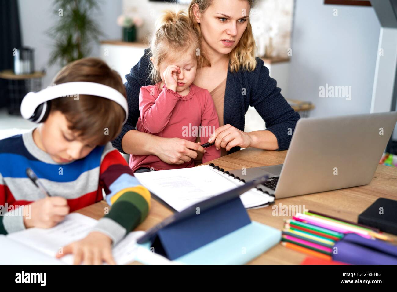 Madre tratando de reconciliar el trabajo remoto con el trabajo en casa Foto de stock