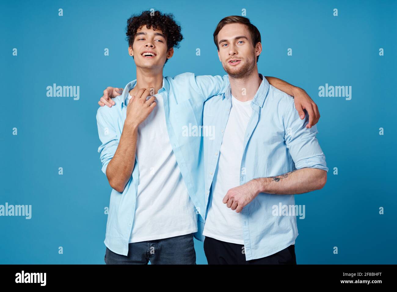 amigos abrazando en un fondo azul divertido a juego camisas blanco  pantalones para camisetas Fotografía de stock - Alamy
